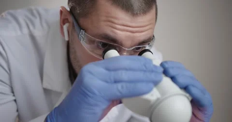 Scientist is observing samples through a microscope Stock Footage 300362517