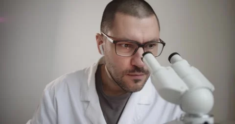 Scientist is observing samples through a microscope 库存影片 300362530