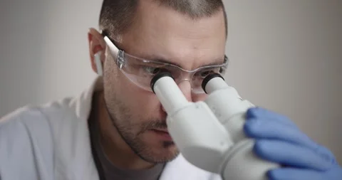 Scientist is observing samples through a microscope Vídeos de archivo 300362572