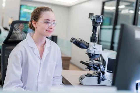 Scientist observing samples under microscope in modern laboratory setting d.. Stock Photos