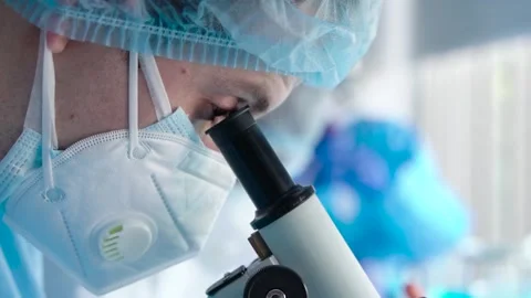 Scientist or researcher in laboratory looking into microscope Stock Footage 132619783
