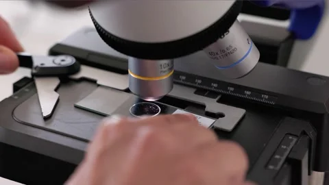 Scientist placing and removing slides from a microscope 스톡 동영상 232008011