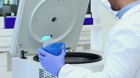 Scientist placing samples in laboratory centrifuge for analysis Stock Footage 296884926
