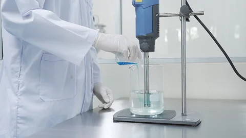 Scientist pour Blue solution into Beaker and use mixing Machine 50fps Stock-Footage 247488085