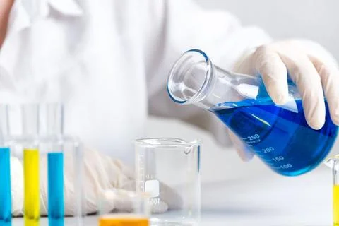 Scientist pouring blue liquid into empty beaker, laboratory experiment and .. Stock-Fotos