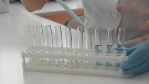 Scientist pouring blue liquid in test tubes in a laboratory Stock Footage 95550486