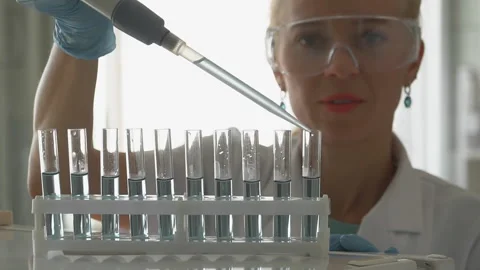 Scientist pouring blue liquid in test tubes in a laboratory Stock Footage 95550728
