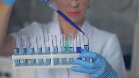 Scientist pouring blue liquid in test tubes in a laboratory Vídeos de archivo 95850786