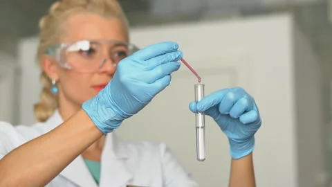 Scientist pouring red liquid in test tubes in a laboratory 스톡 동영상 95550291