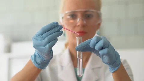 Scientist pouring red liquid in test tubes in a laboratory Stock Footage 95550374
