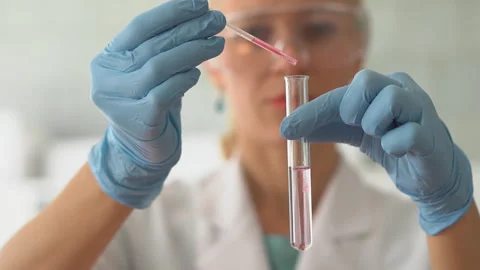 Scientist pouring red liquid in test tubes in a laboratory Stock Footage 95550404