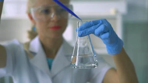 Scientist pouring red liquid in test tubes in a laboratory Stock Footage 95596145