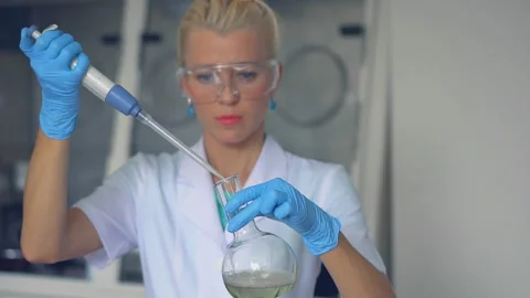 Scientist pouring red liquid in test tubes in a laboratory Stock Footage 95851183