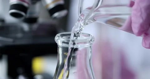 Scientist pours clear liquid into flask slow motion 4k movie Stock Footage 166692516