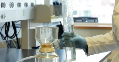 Scientist pours fluid between beakers Stock Footage 114181704