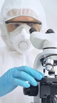 Scientist in ppe analyzing samples and analyzing samples with a microscope in a 写真素材