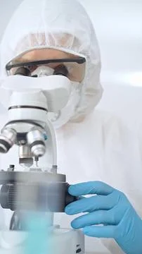 Scientist in ppe analyzing samples and analyzing samples with a microscope in a Stock Photos