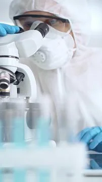 Scientist in ppe analyzing samples with microscope. Close-up of a focused Stock-Fotos