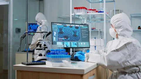 Scientist in ppe suit typing codes on pc Stock Photos
