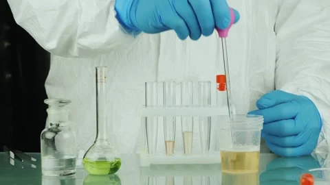 Scientist in protective gear meticulously performs chemical experiment usin.. Stockbeeldmateriaal 334531693