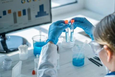 Scientist in protective gloves analyzing chemical samples in test tubes at Stock Photos