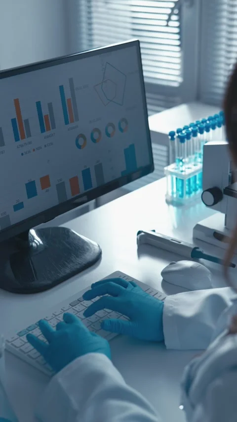 Scientist in protective gloves analyzing scientific data on a computer screen in Stock Footage 341036580