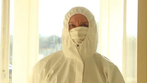 Scientist in a protective suit and mask walks toward camera and looking around Stock Footage 144745063