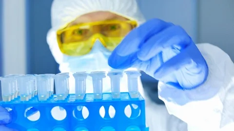 Scientist in protective suit checking dangerous substance in test tubes Stock Footage 108648954