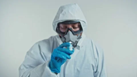 Scientist in protective suit, goggle and mask shows COVID-19 vaccine and drinks Stock Footage 143532517