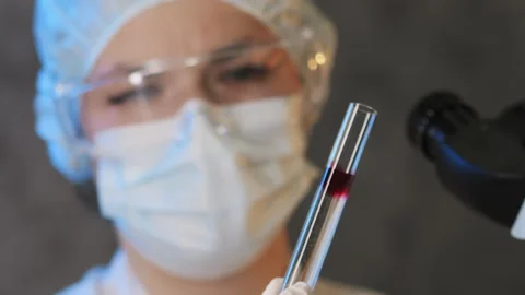 A scientist in a protective suit holds a test tube with a sample. Stock Footage 302177338
