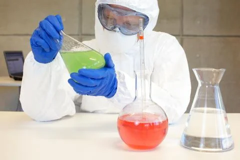 Scientist in protective uniform working in lab with glassware Stock Photos