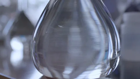 Scientist pulls flask of water off table and reveals other flasks Stock Footage 92499529