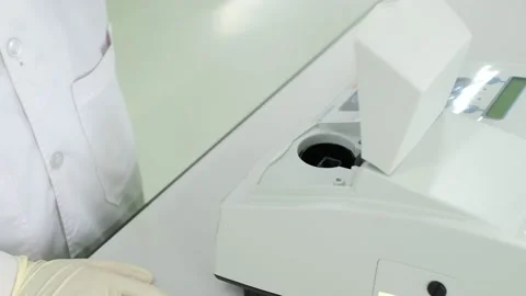 Scientist put a pink sample in quartz cuvette into UV spectroscopy machine Stock Footage 139346235