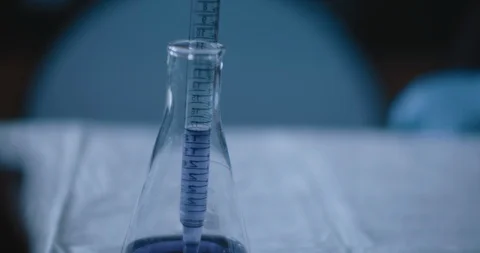Scientist put a purple liquid into a conical flask in a lab,slow motion,tracking Stock Footage 121058304