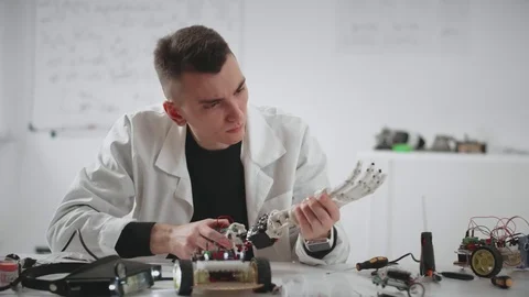 Scientist researcher constructing and testing robotic hand prosthesis at table Stock Footage 83752491