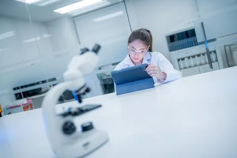 Scientist reviews data on tablet in laboratory setting during daytime hours Stock Photos