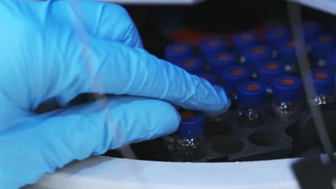 Scientist in rubber gloves puts HPLC vials into the auto sample for measuremetns Stock Footage 194007599