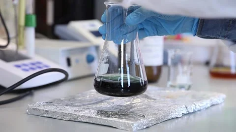 Scientist shaking Erlenmeyer Flask with liquid in a laboratory, slider shot Stock Footage 61713154