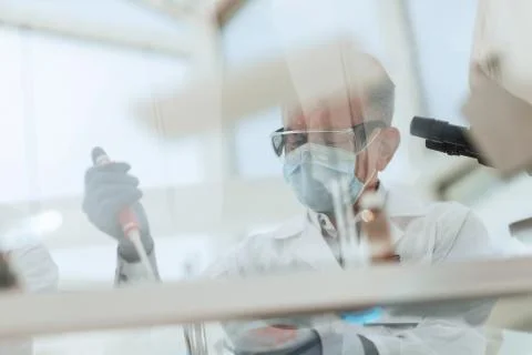 Scientist sitting using an automatic dispenser for his research. Stock Photos