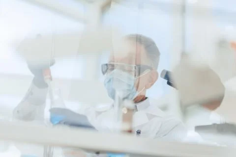 Scientist sitting using an automatic dispenser for his research. Stock Photos