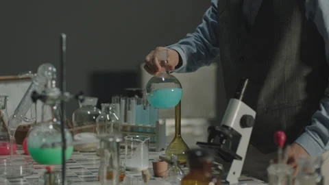 A scientist slowly shakes a blue liquid in a flask in a lab Stock Footage 336233101