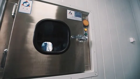 Scientist in sterile clothes takes stack of trays out desinfection chamber Stock Footage 76614855