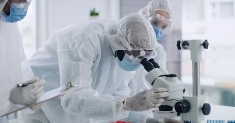 Scientist, team and microscope with PPE, discussion and clipboard for medic.. Stock Photos