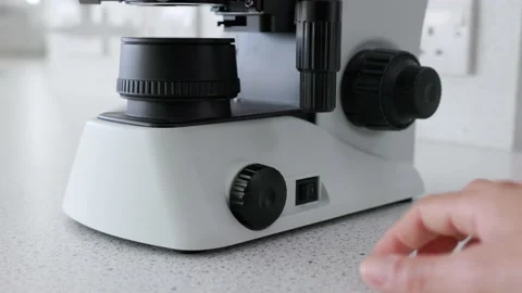 Scientist turning on microscope and adjusting microscope light source 스톡 동영상 232007808
