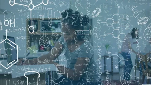 Scientist typing on laptop showing molecules and noting findings while glancing Stockbeeldmateriaal 315559261