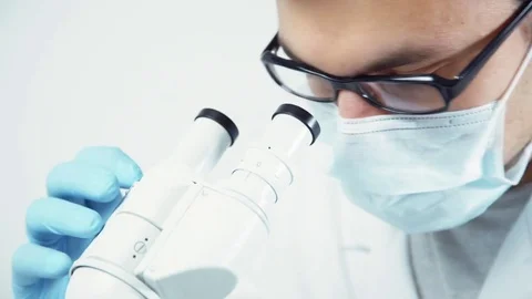 Scientist in uniform looking at microscope Stock Footage 82320139