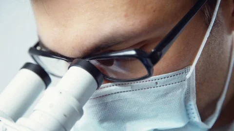 Scientist in uniform looking at microscope 動画素材 82320444