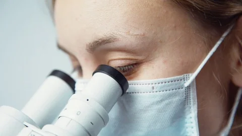 Scientist in uniform looking at microscope 動画素材 82322539