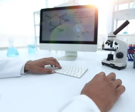 A scientist uses a computer and a microscope 스톡 사진