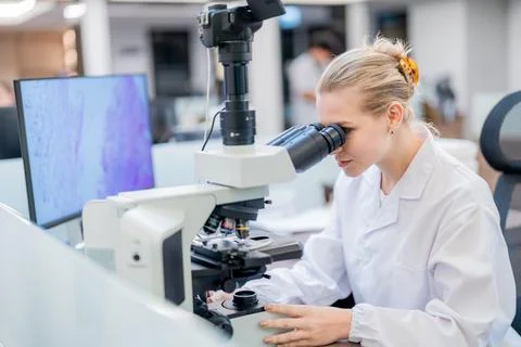 Scientist uses microscope to analyze samples in modern laboratory setting d.. Stock Photos